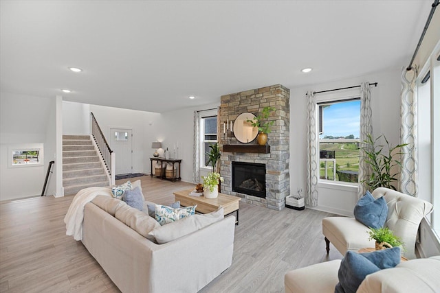 10082 Arrowwood Trl, Woodbury, MN 55129 - living room featuring stairway, light wood finished floors, a stone fireplace, and recessed lighting