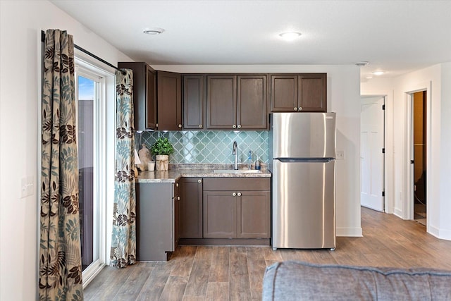 10082 Arrowwood Trl, Woodbury, MN 55129 - kitchen featuring freestanding refrigerator, light wood finished floors, dark brown cabinets, and decorative backsplash