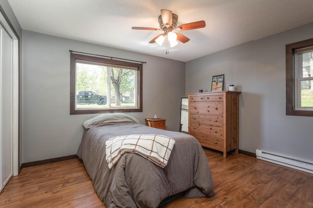 2510 Conifer Ave, Alexandria, MN 56308 - bedroom featuring a baseboard radiator, wood finished floors, and baseboards