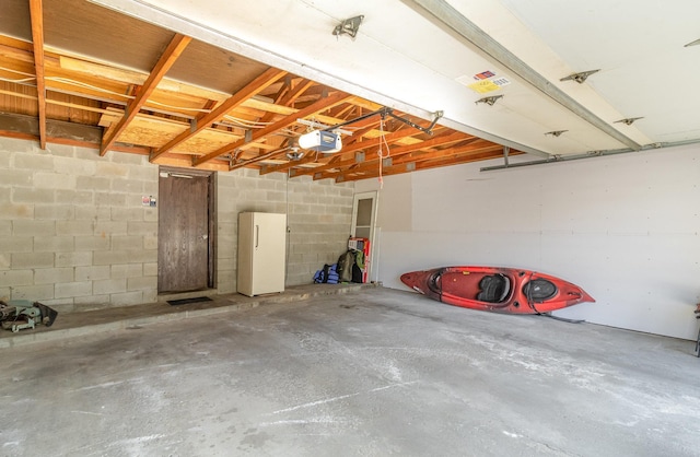 6872 Grenwich Ln N Unit 0, Oakdale, MN 55128 - garage featuring a garage door opener, concrete block wall, and freestanding refrigerator
