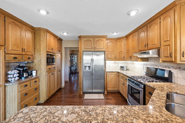 14573 Krypton St NW, Ramsey, MN 55303 - kitchen featuring stainless steel appliances, under cabinet range hood, dark wood-style floors, tasteful backsplash, and a textured ceiling