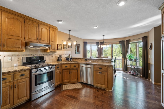 14573 Krypton St NW, Ramsey, MN 55303 - kitchen featuring appliances with stainless steel finishes, under cabinet range hood, brown cabinetry, a sink, and a textured ceiling