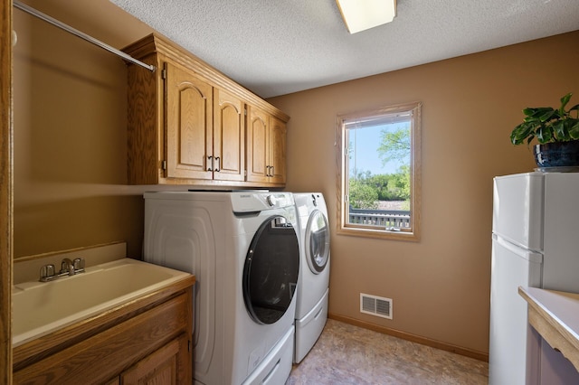 14573 Krypton St NW, Ramsey, MN 55303 - washroom featuring separate washer and dryer, baseboards, cabinet space, and a textured ceiling