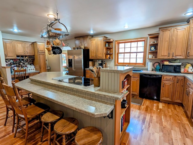617 9th St, Montevideo, MN 56265 - kitchen with open shelves, black appliances, a center island, a kitchen breakfast bar, and light wood-type flooring