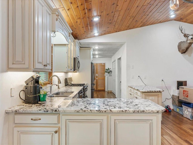 30703 Lakeview Dr, Breezy Point, MN 56472 - kitchen featuring appliances with stainless steel finishes, cream cabinetry, a sink, light wood-type flooring, and vaulted ceiling