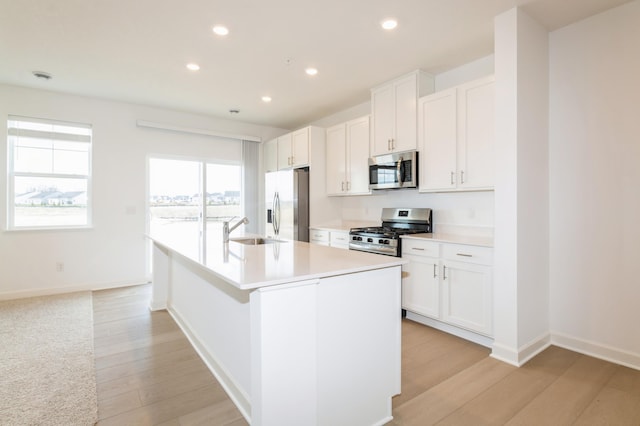 kitchen featuring appliances with stainless steel finishes, a sink, an island with sink, recessed lighting, and light wood-type flooring