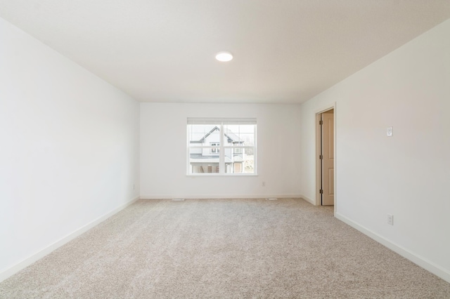 spare room featuring light carpet, baseboards, and recessed lighting