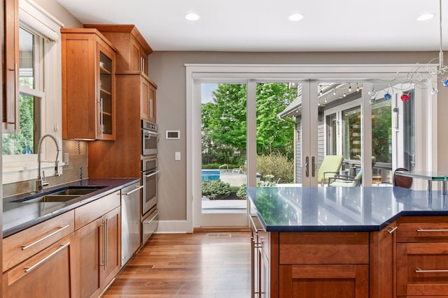 154 Babcock Ln, Wayzata, MN 55391 - kitchen featuring a sink, brown cabinetry, light wood-style flooring, glass insert cabinets, and recessed lighting