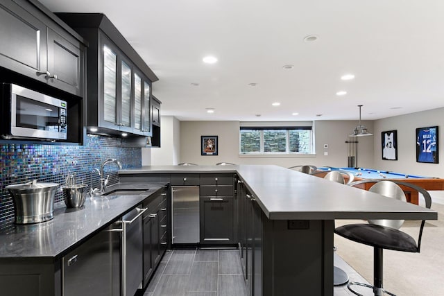 154 Babcock Ln, Wayzata, MN 55391 - kitchen featuring stainless steel microwave, a sink, a peninsula, a breakfast bar area, and decorative backsplash