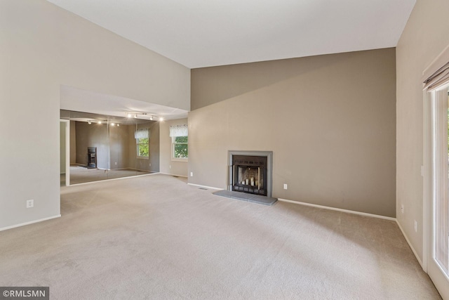 11031 Oregon Cir Unit 58, Bloomington, MN 55438 - unfurnished living room with baseboards, carpet, a fireplace with raised hearth, and high vaulted ceiling