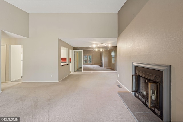 11031 Oregon Cir Unit 58, Bloomington, MN 55438 - unfurnished living room with a fireplace with raised hearth, carpet flooring, baseboards, and a towering ceiling