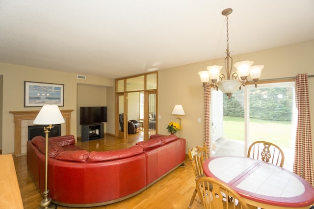 1675 Skywood Ln, Eagan, MN 55122 - living room featuring a tile fireplace, light wood-style floors, and a chandelier