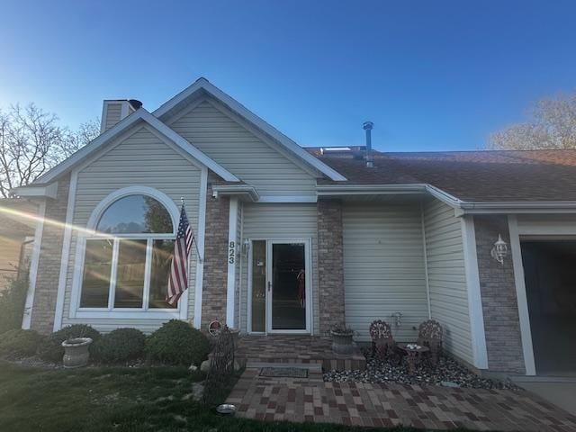 back of property with a chimney and brick siding