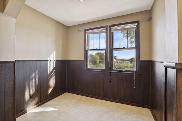 1264 Snelling Ave N, Saint Paul, MN 55108 - unfurnished room with wainscoting, light floors, wood walls, and a textured ceiling
