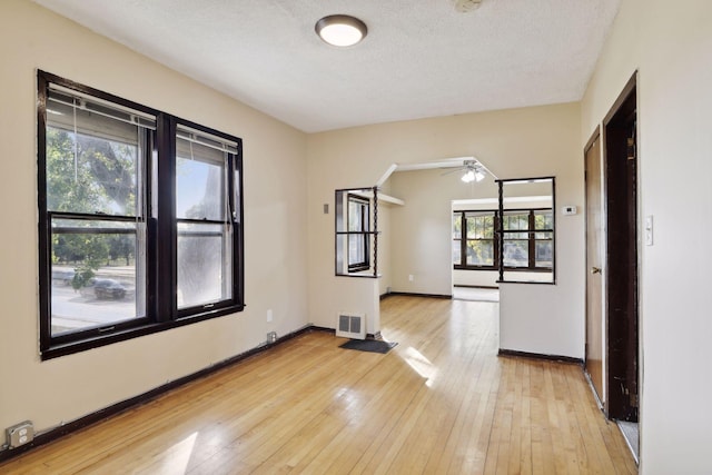 1264 Snelling Ave N, Saint Paul, MN 55108 - spare room with light wood-type flooring, a ceiling fan, a textured ceiling, and baseboards