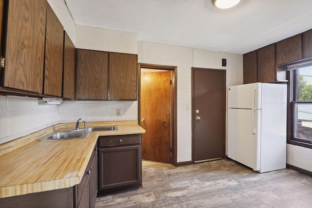 1264 Snelling Ave N, Saint Paul, MN 55108 - kitchen featuring freestanding refrigerator, a sink, light wood finished floors, dark brown cabinetry, and a textured ceiling