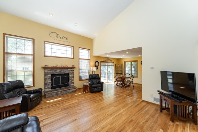 living area with a fireplace, light wood-style flooring, high vaulted ceiling, and recessed lighting