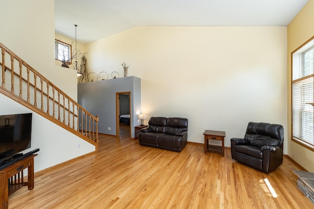 sitting room featuring wood finished floors, stairs, and high vaulted ceiling