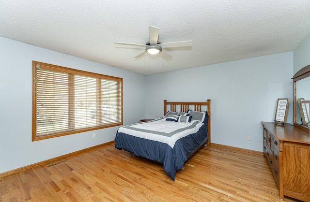 bedroom with light wood finished floors, baseboards, and ceiling fan