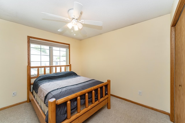 bedroom featuring light colored carpet, baseboards, and a ceiling fan