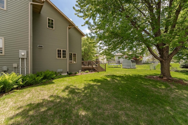 view of green lawn with a wooden deck