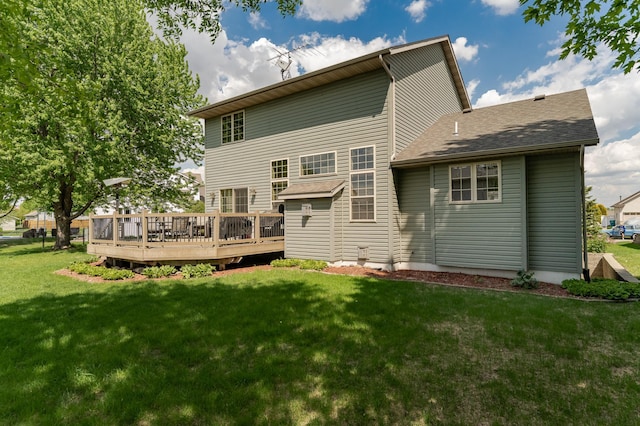 rear view of house with a wooden deck, a lawn, and roof with shingles