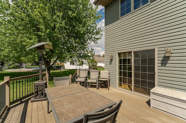 wooden terrace with outdoor dining space and a yard