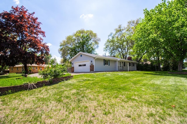 back of property with a garage, a yard, a chimney, and driveway