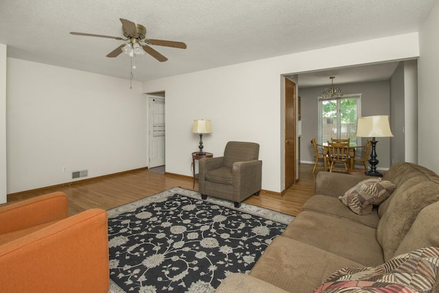 living area featuring wood finished floors, ceiling fan, baseboards, and a chandelier