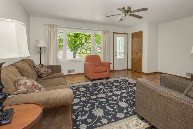 living room featuring wood finished floors, a ceiling fan, and baseboards