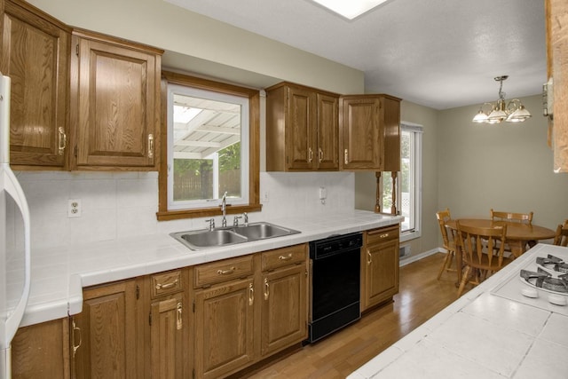 kitchen featuring black dishwasher, a sink, healthy amount of natural light, and tile countertops