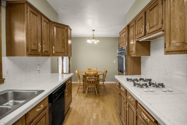 kitchen with dishwasher, tile countertops, stainless steel oven, decorative backsplash, and brown cabinetry