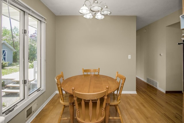 dining room featuring a chandelier, light wood-type flooring, and baseboards