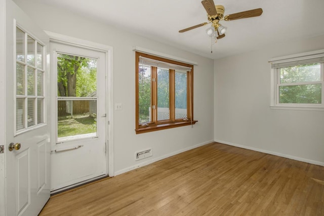 empty room with plenty of natural light, light wood finished floors, and baseboards