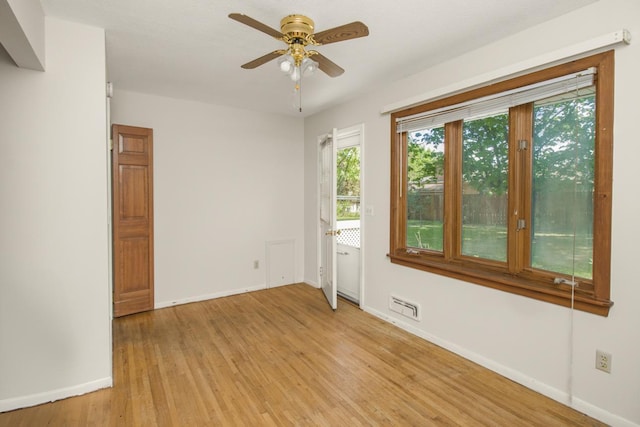 spare room featuring baseboards, ceiling fan, and light wood finished floors