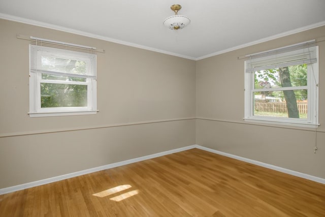 empty room featuring baseboards, wood finished floors, plenty of natural light, and ornamental molding