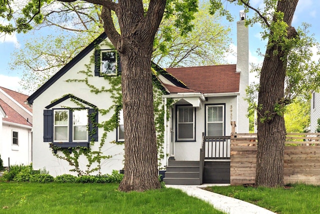 view of front of property featuring stucco siding, a chimney, and fence