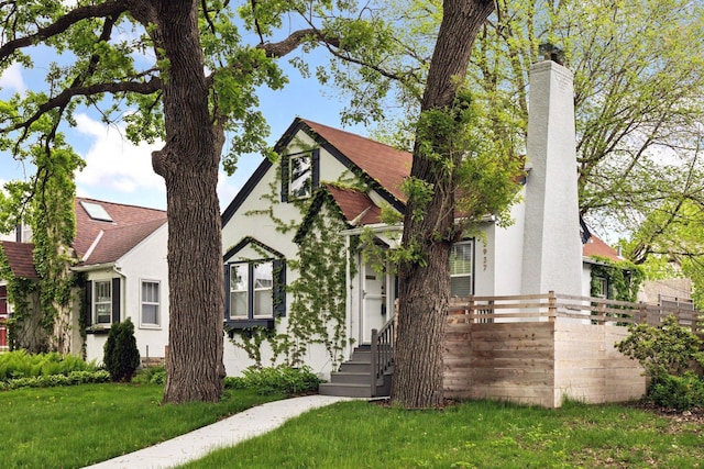 english style home featuring stucco siding and a chimney