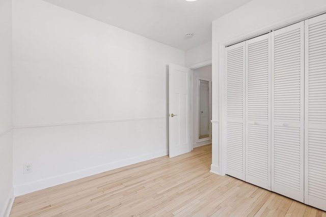 unfurnished bedroom with wood finished floors, a closet, and baseboards