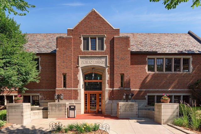 view of front facade featuring brick siding, french doors, and a high end roof