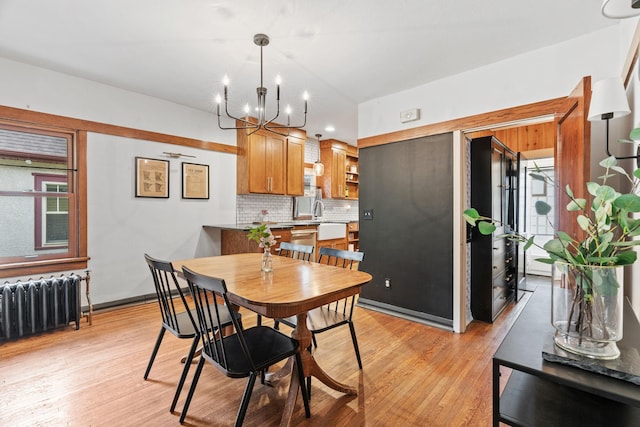 dining space featuring radiator heating unit, a chandelier, light wood-style floors, and healthy amount of natural light