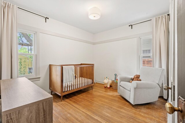 bedroom featuring light wood-style floors and a crib