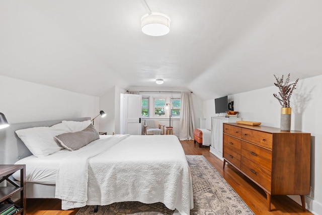 bedroom with wood finished floors and lofted ceiling