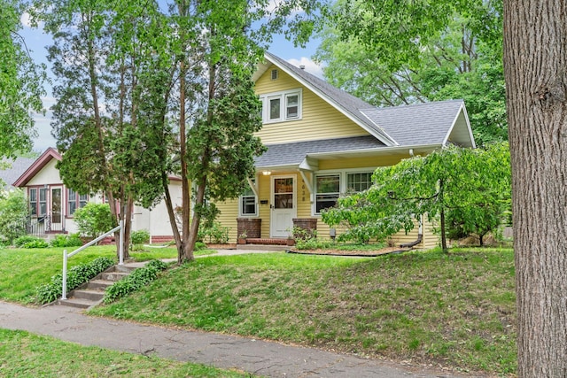 view of front facade with a shingled roof and a front yard