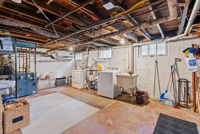 basement with washer and clothes dryer, a sink, and a heating unit