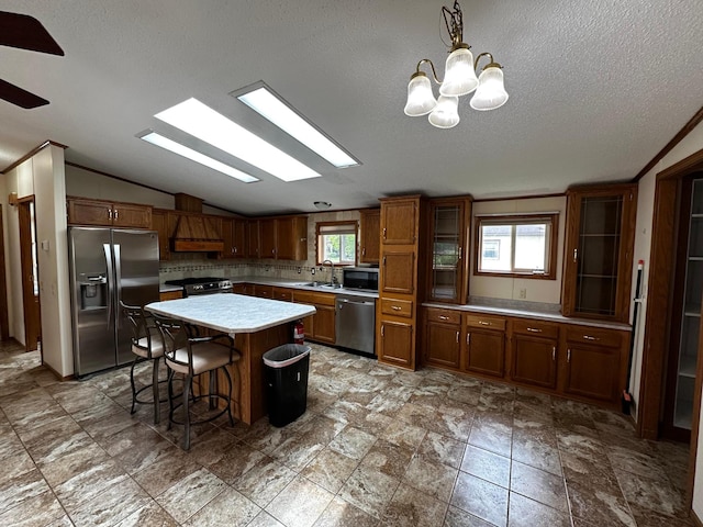 326 5th St NE, Crosby, MN 56441 - kitchen featuring stainless steel appliances, vaulted ceiling, a sink, light countertops, and brown cabinetry