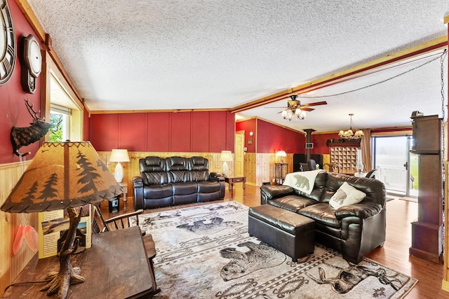 living room featuring a wood stove, a textured ceiling, wooden walls, ceiling fan, and wood finished floors