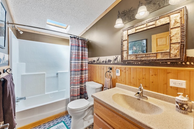 full bathroom with a skylight, toilet, a wainscoted wall, a textured ceiling, and shower / bath combo with shower curtain