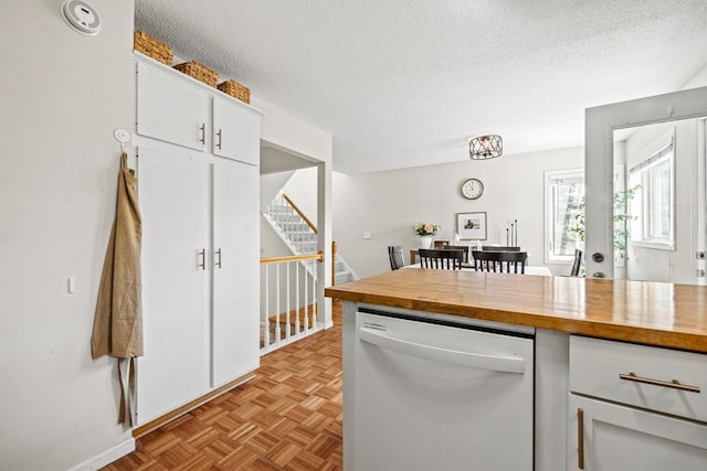 1715 Livingston Ave Unit A, West Saint Paul, MN 55118 - kitchen with white dishwasher, butcher block counters, a textured ceiling, white cabinets, and baseboards