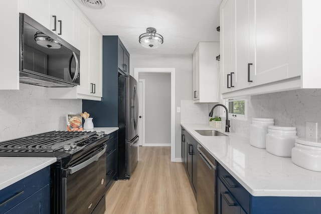 1805 Melrose Ave, Saint Louis Park, MN 55426 - kitchen featuring appliances with stainless steel finishes, a sink, blue cabinets, light wood-type flooring, and decorative backsplash